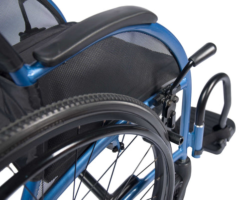 Close-up of the Strongback Comfort S push-to-lock parking brake engaged at the rear wheel, beside the desk-length armrest