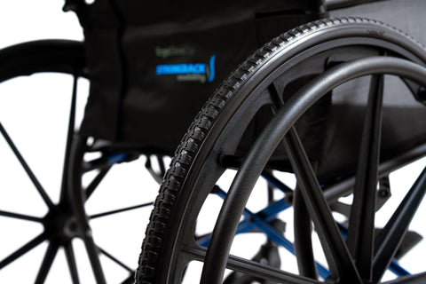Close-up of the ErgoSteel 24 inch rear wheel and handrim, with the ErgoSteel logo on the backrest behind