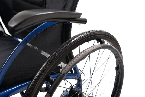 Close-up of the desk-length armrest and 24 inch rear wheel with hand rim on the Strongback Comfort Flip