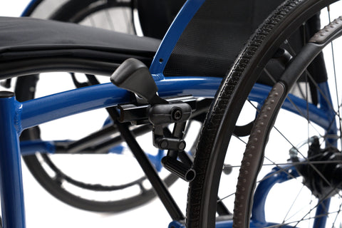 Close-up of the flip-back armrest mounting hardware on the blue frame of the Strongback Comfort Flip, beside the 24 inch rear wheel