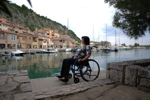 Woman seated in a blue Strongback Comfort S wheelchair looking out over the marina at Porto Piccolo